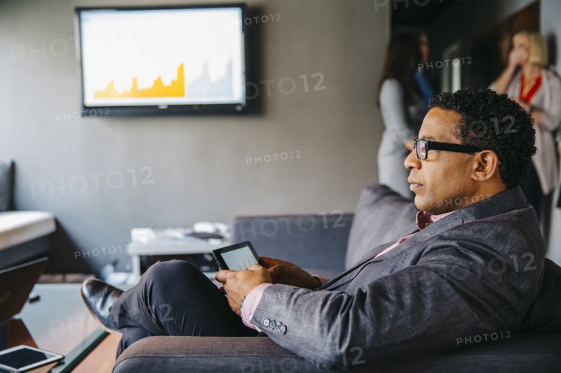 Mixed race businessman using digital tablet in office lounge