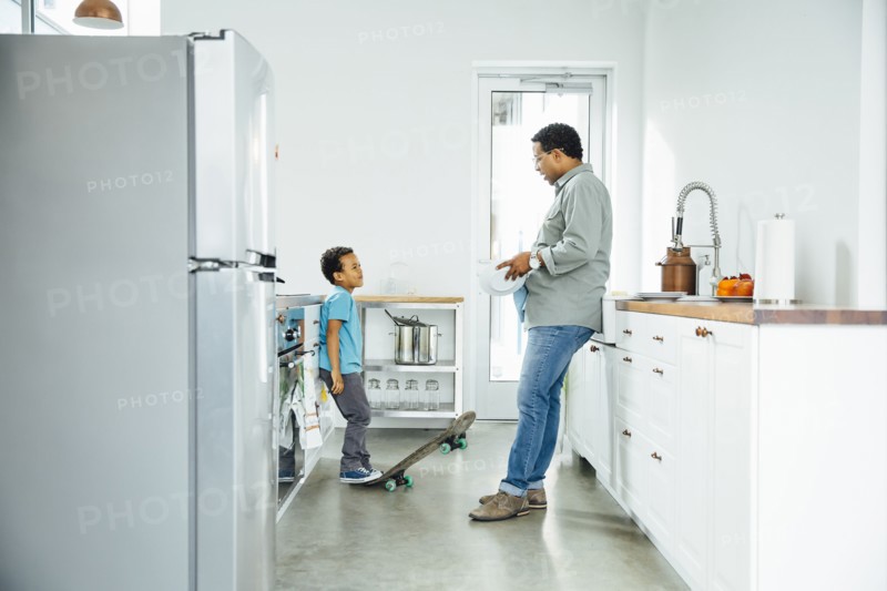 Father scolding son for skateboarding in kitchen