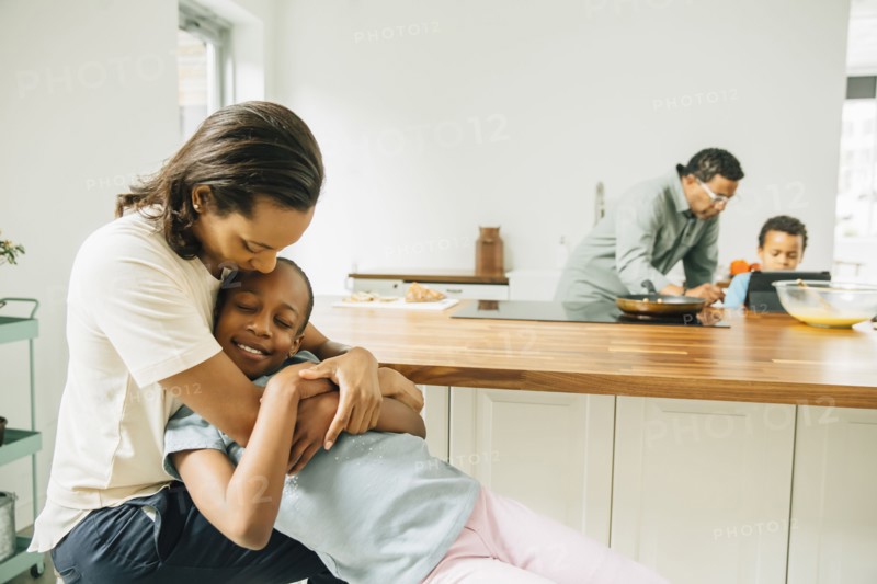 Mother hugging daughter in kitchen