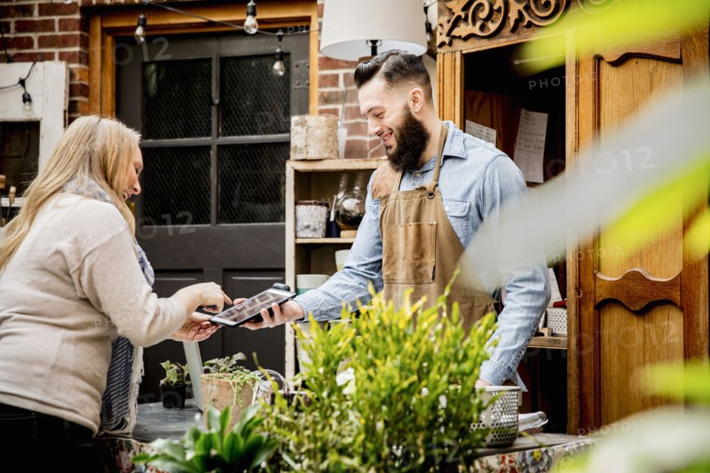 Employee helping customer with digital tablet in store
