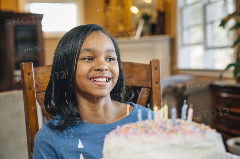 Black girl blowing out candles on birthday cake