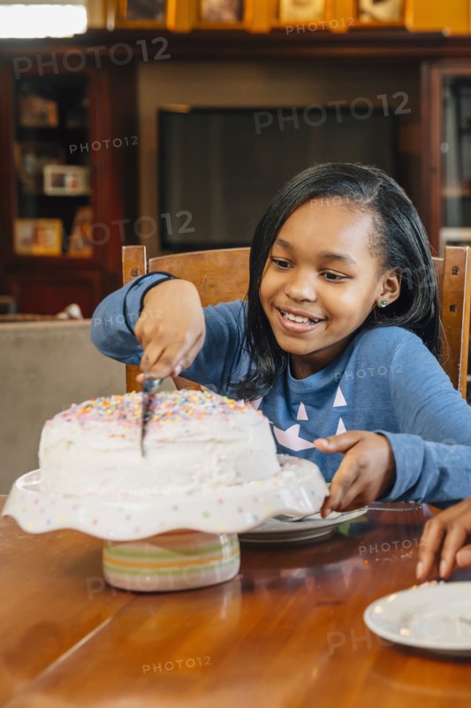 Black girl cutting cake at birthday party
