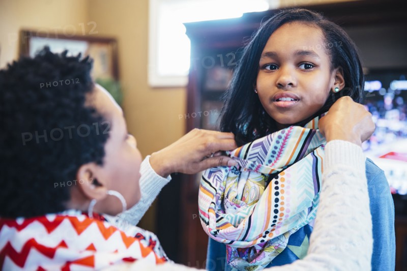 Black mother arranging scarf of daughter