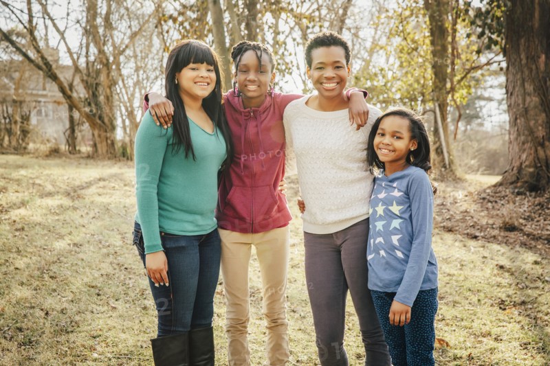 Black mother and daughters smiling outdoors