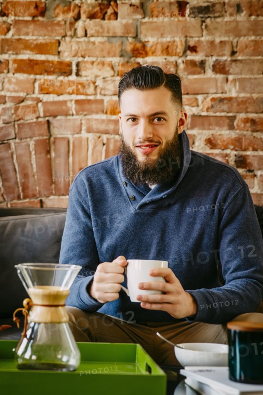 Man drinking coffee on sofa in living room