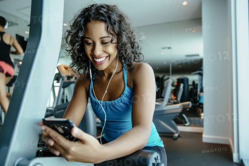 Woman listening to earbuds in gymnasium