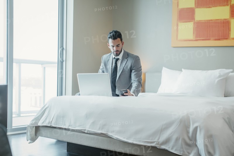 Businessman using laptop on hotel bed