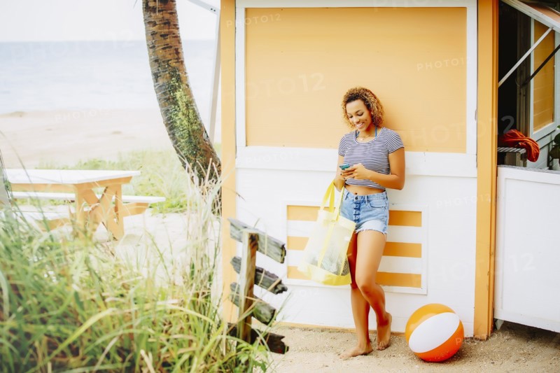 Mixed race teenager using cell phone on beach