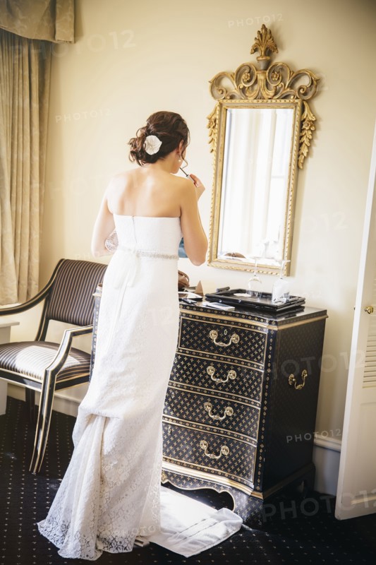 Caucasian bride applying makeup in mirror