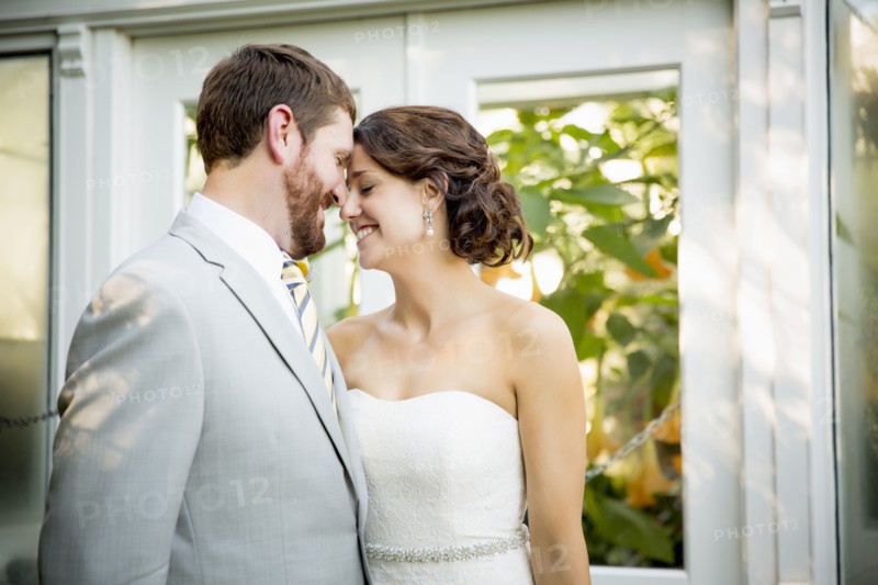 Caucasian bride and groom touching foreheads in garden