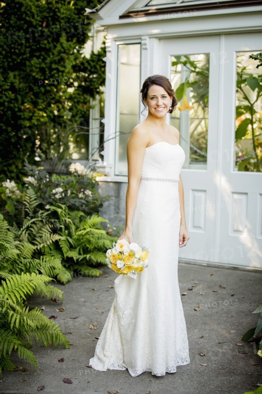 Caucasian bride holding bouquet in garden