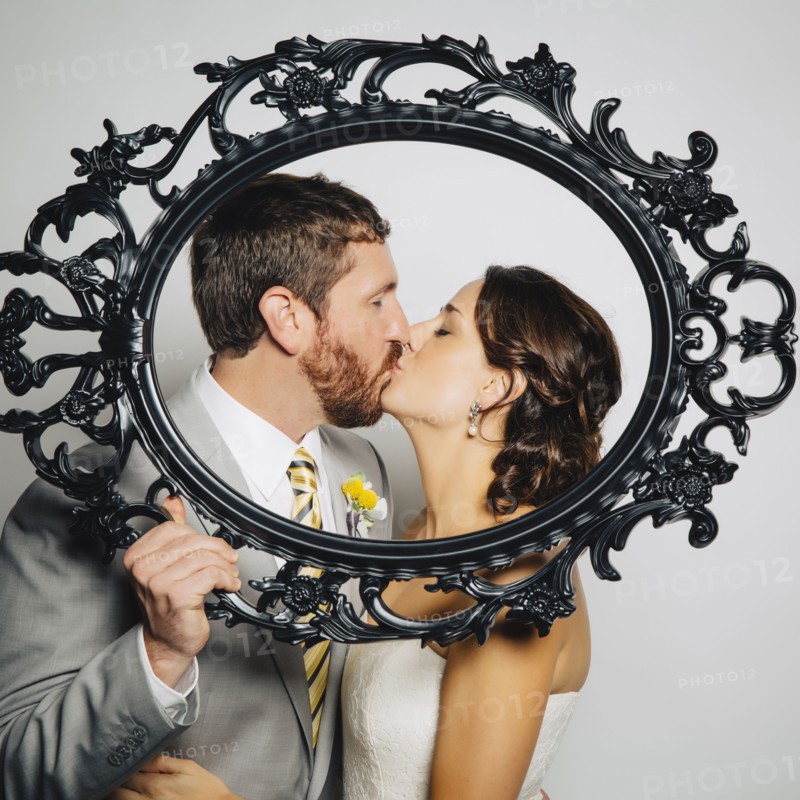 Caucasian bride and groom kissing behind empty frame