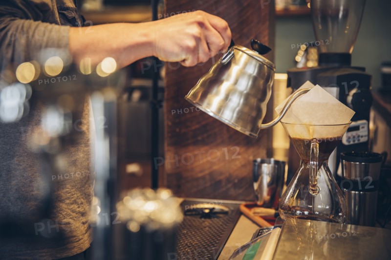 Caucasian barista pouring hot water over coffee in cafe