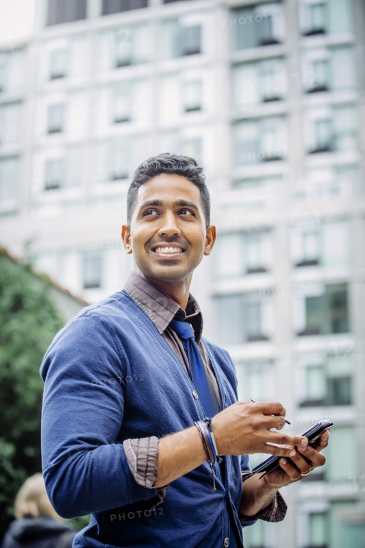 Indian businessman using cell phone outdoors