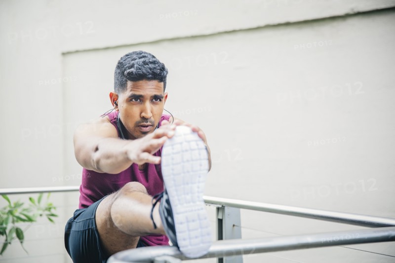 Indian man stretching on banister