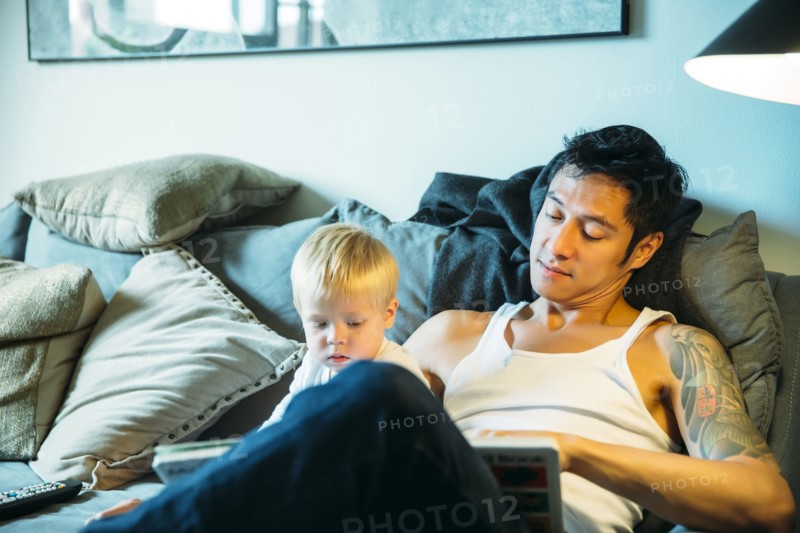 Father and son reading on sofa in living room