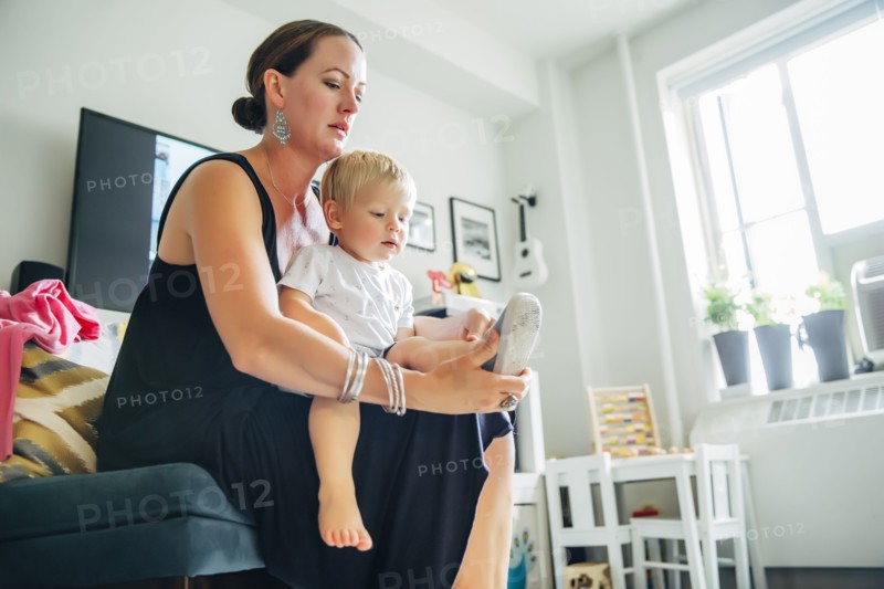 Mother helping son put on shoes in living room