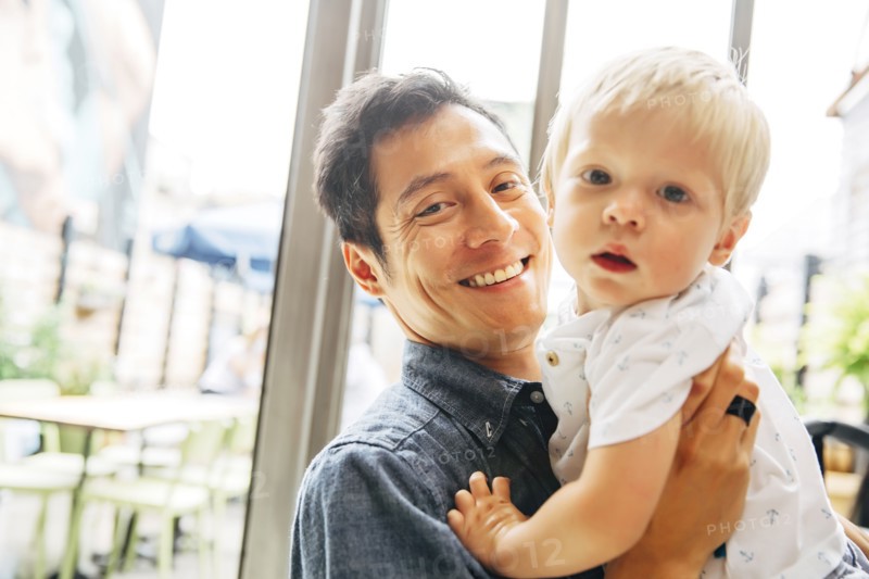 Smiling father holding son by window