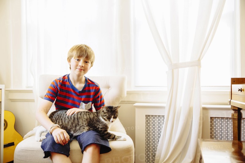 Caucasian boy petting cat in living room