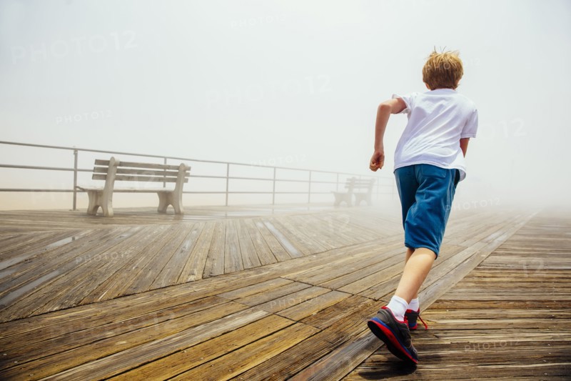 Caucasian boy running on wooden boardwalk