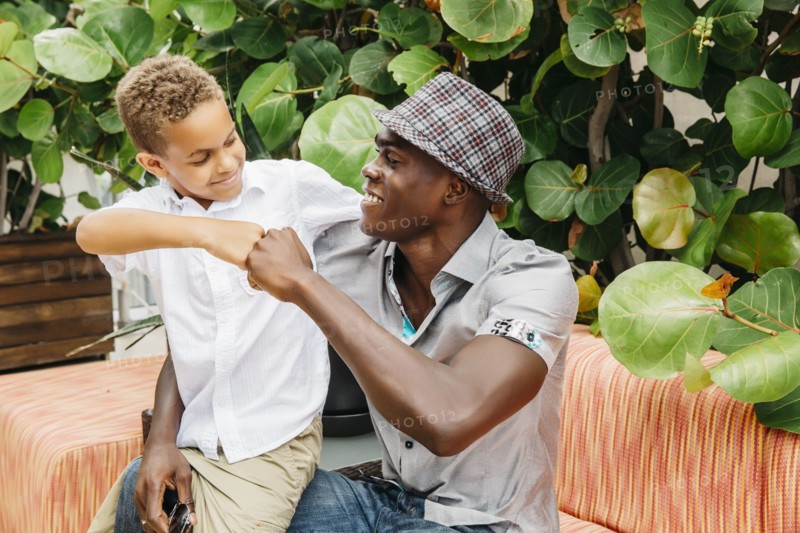 Father and son giving fist bump in backyard