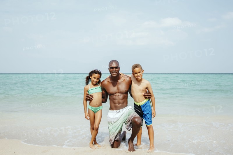 Father and children hugging on beach