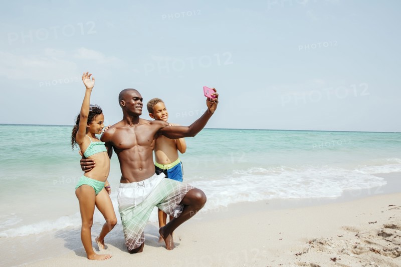 Father and children taking selfie on beach