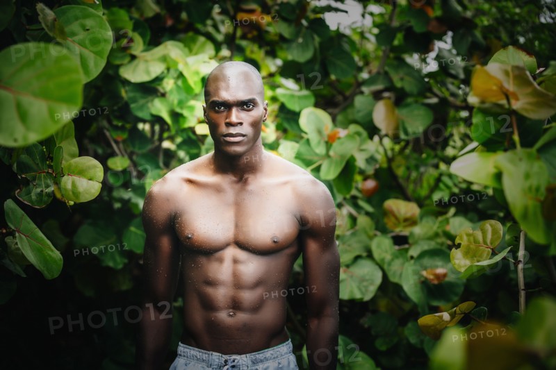 Black man standing in lush garden