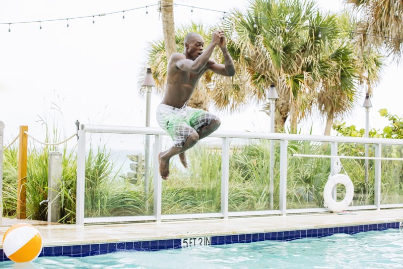 Black man jumping into swimming pool