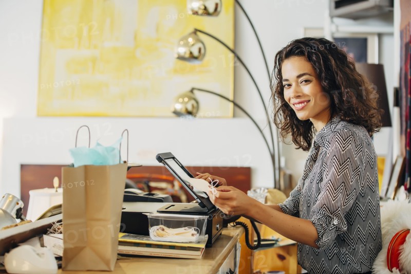 Mixed race clerk using register in shop