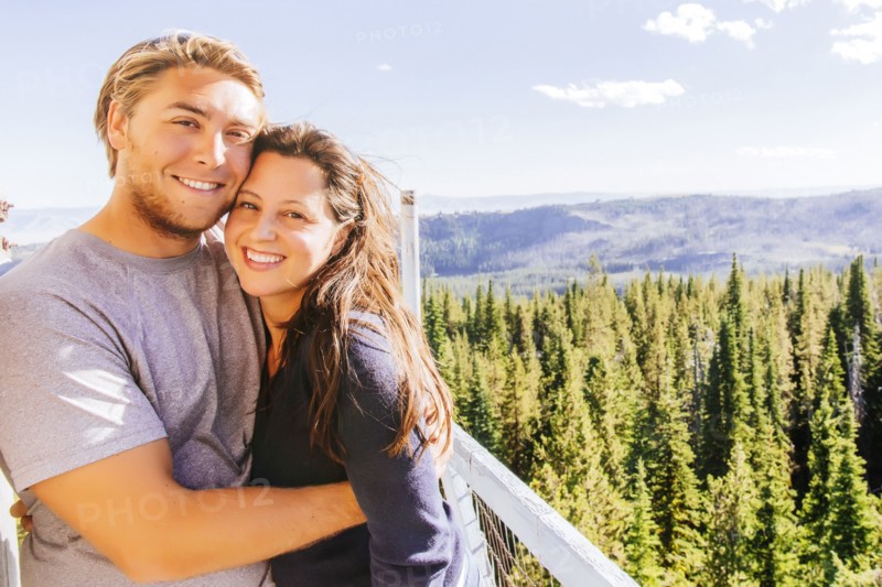 Caucasian couple hugging over forest treetops