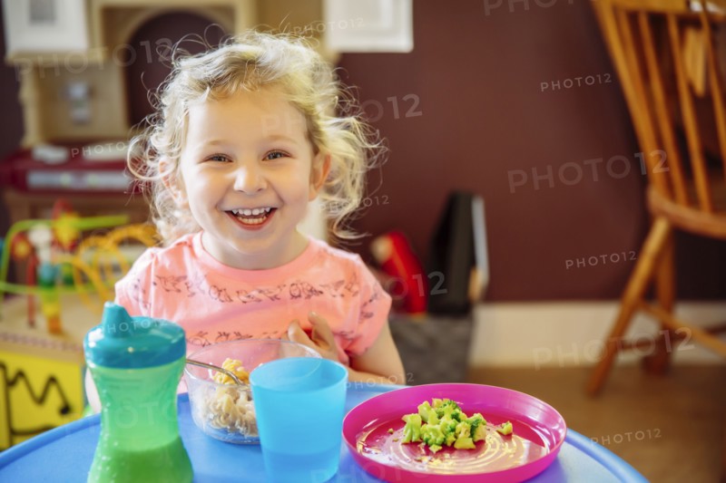 Caucasian girl eating in high chair
