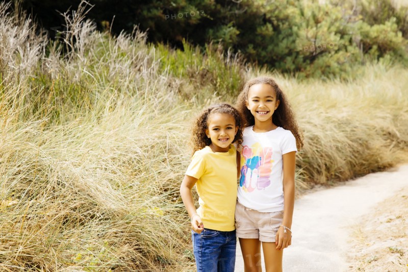 Mixed race sisters smiling on dirt path