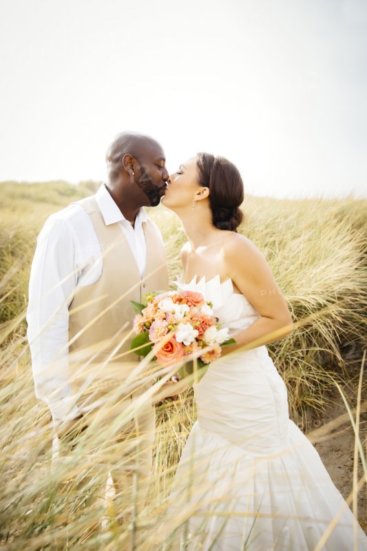 Newlywed couple kissing in grass