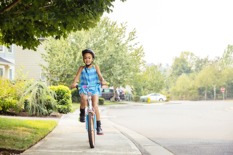 Mixed race girl riding bicycle on sidewalk