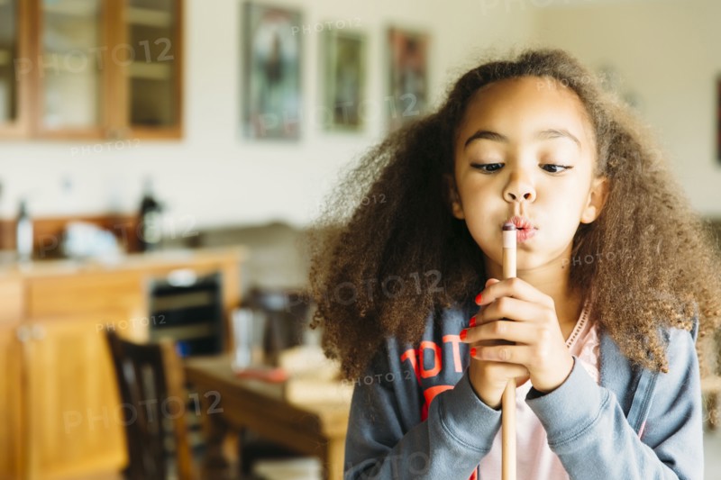 Mixed race girl blowing on pool cue