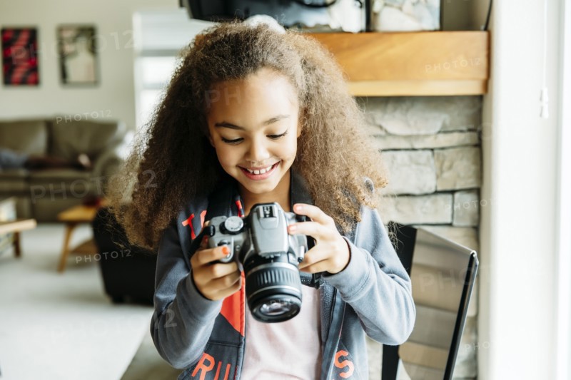 Mixed race girl using camera in living room