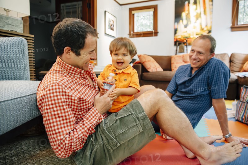 Gay fathers playing with baby son in living room
