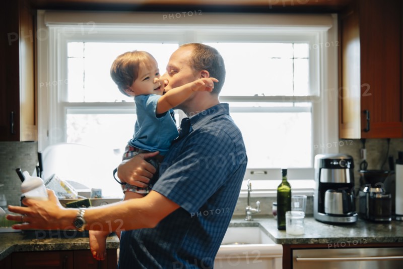 Father kissing baby son in kitchen