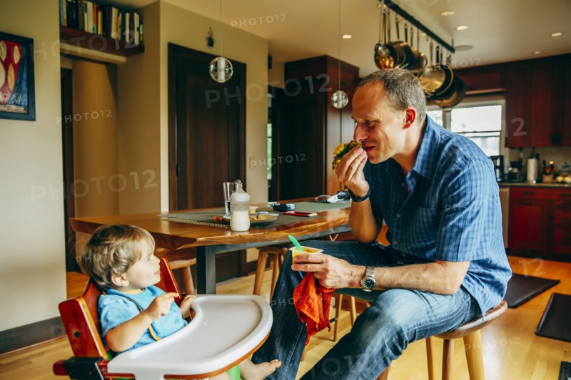 Father feeding baby son in high chair
