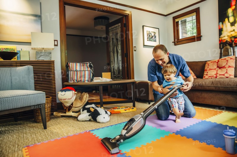 Father and son vacuuming living room