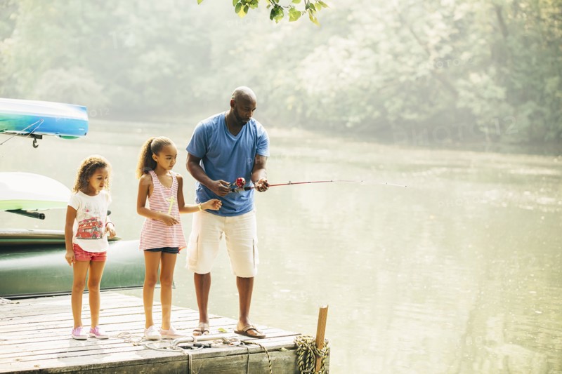 Father and daughters fishing in lake