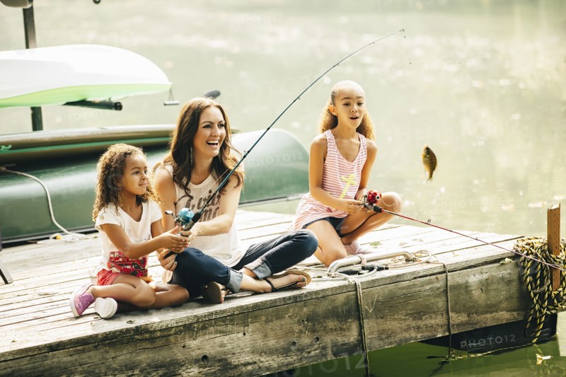 Mother and daughters fishing in lake