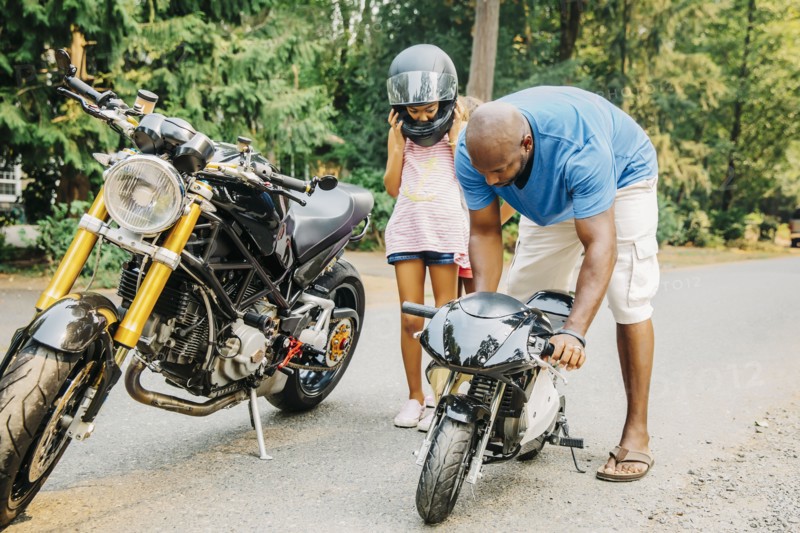 Father helping daughter with miniature motorcycle