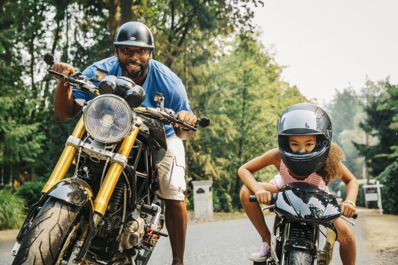 Father and daughter sitting on motorcycles