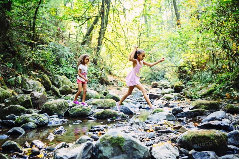 Mixed race sisters exploring stream