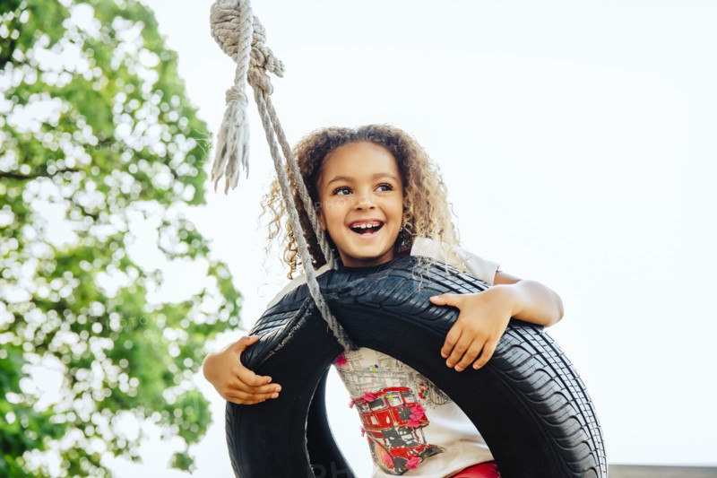 Mixed race girl smiling in tire swing