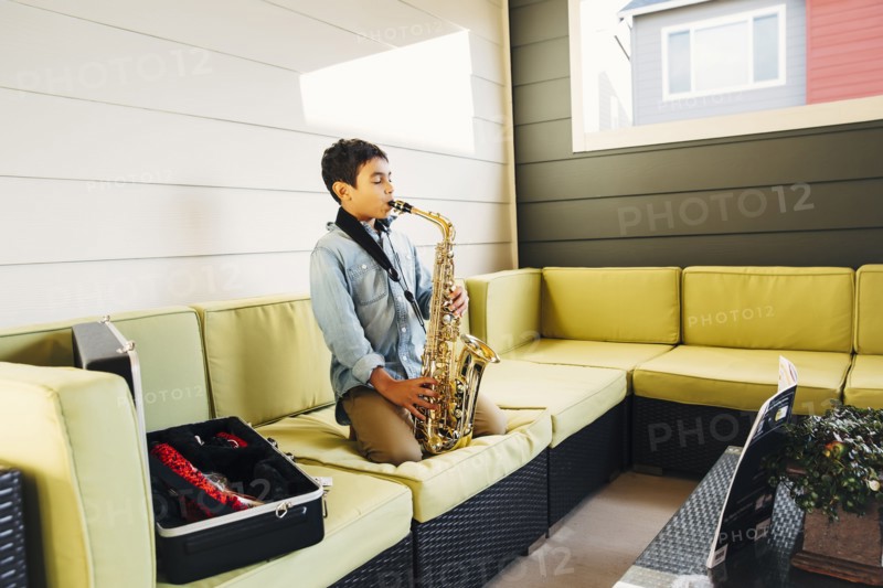 Mixed race boy playing saxophone on sofa