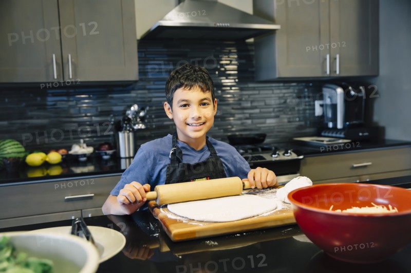 Mixed race boy rolling dough in kitchen