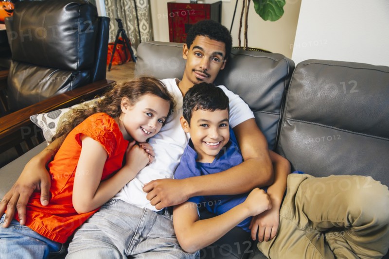 Mixed race brothers and sister laying on sofa